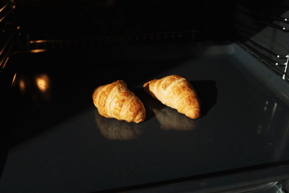 Golden freshly baked croissants on a tray in an oven