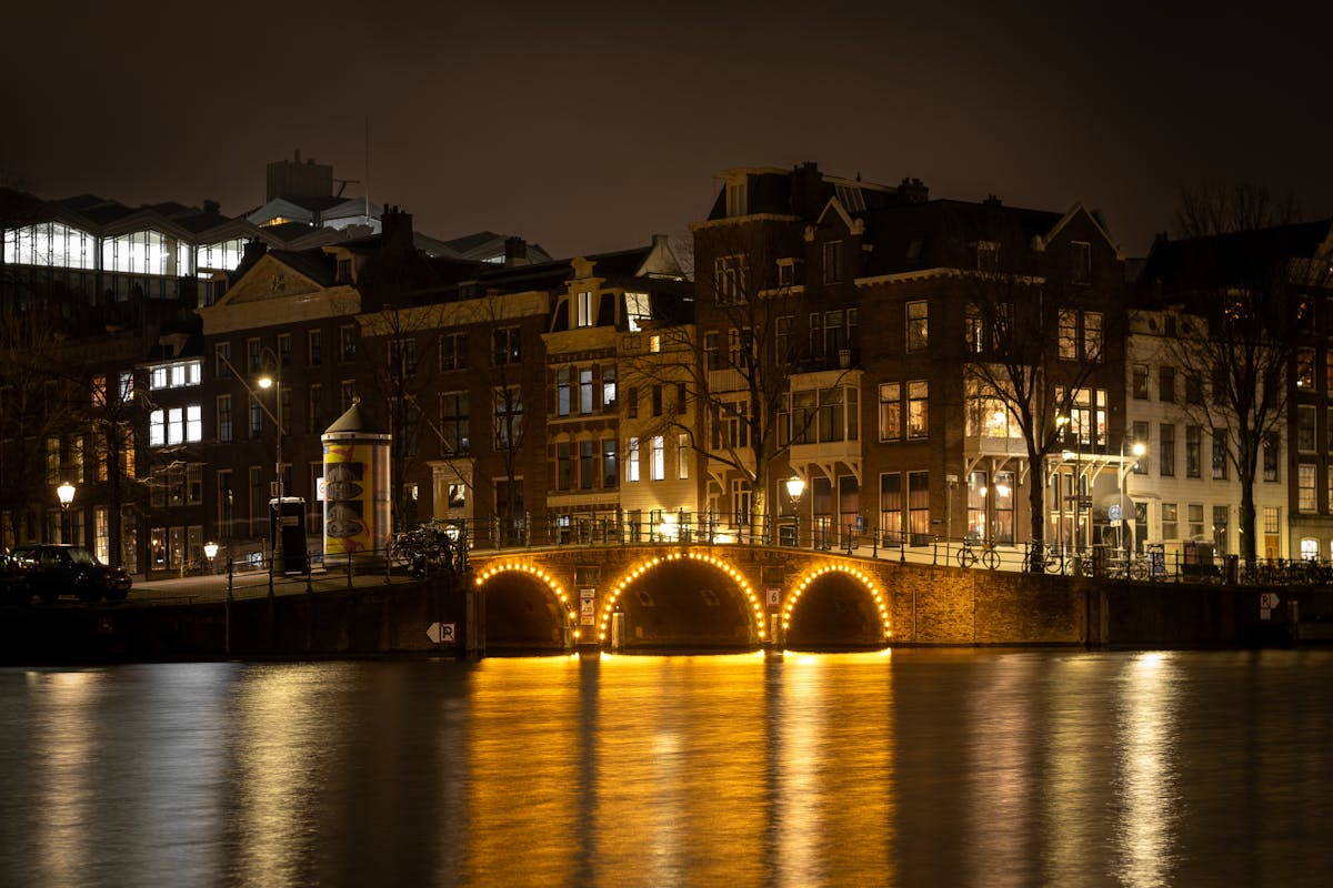 Scenic view of an illuminated canal bridge and traditional architecture in Amsterdam at night