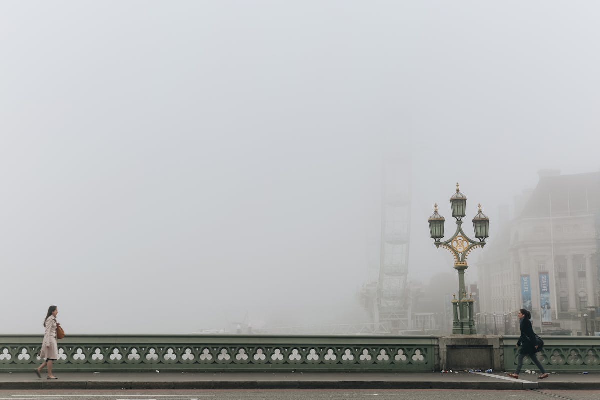 People walking across Westminster Bridge on a misty foggy morning in London