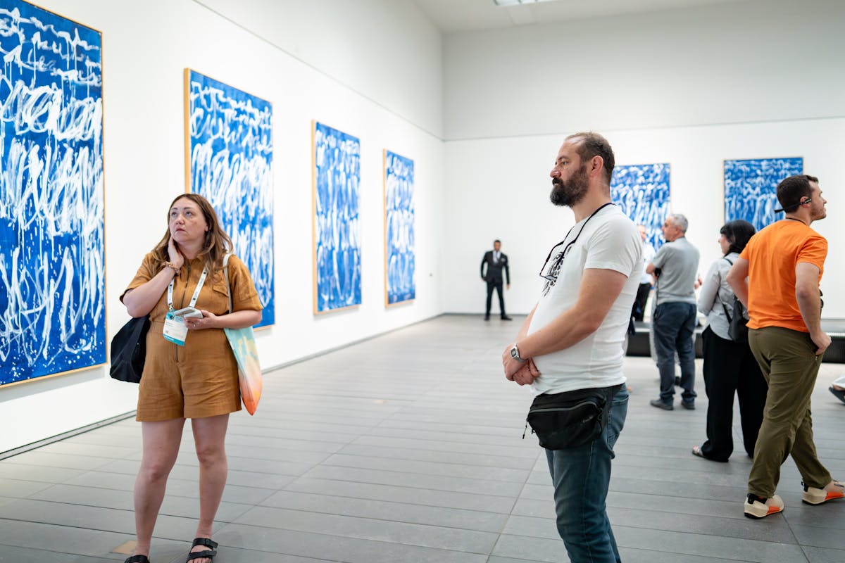 Visitors in an art gallery engaging with blue abstract artworks