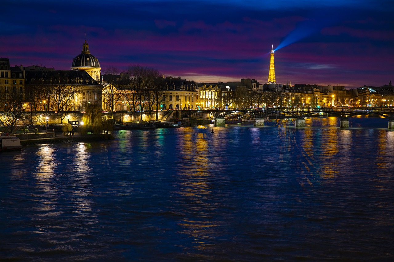 Paris cityscape at night with bridges illuminated and reflecting on the Seine