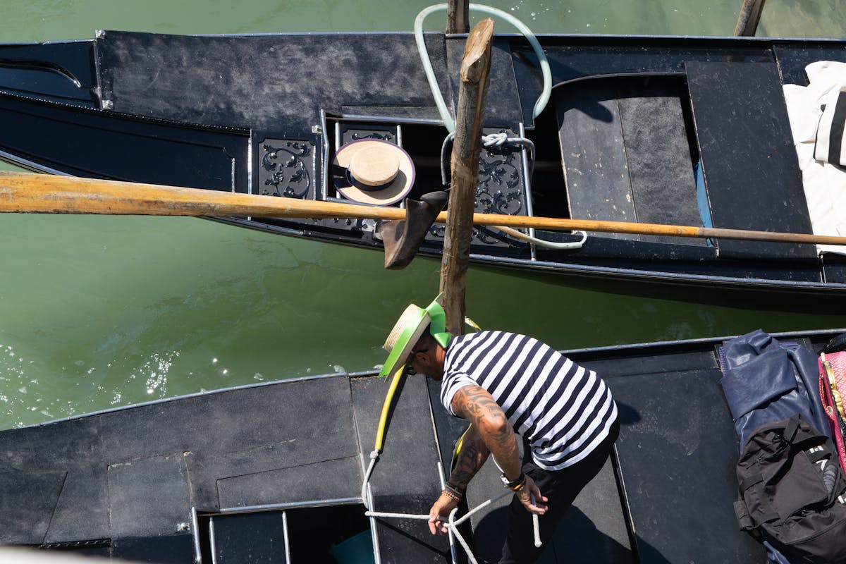 Gondolier adjusting ropes on a gondola in Venice