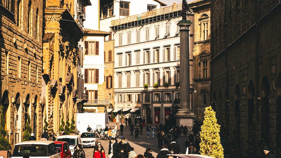 Colorful historic buildings along a Florence street with cathedral dome visible