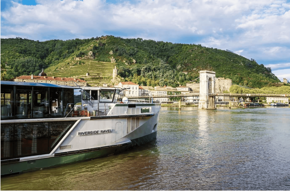 Elegant cruise ship travels along scenic river near French vineyards