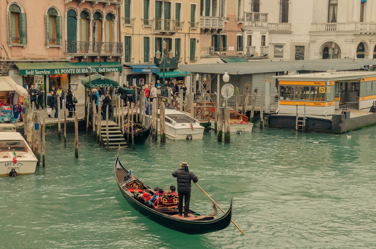 Gondolier navigating a gondola along a Venice canal near Rialto Bridge