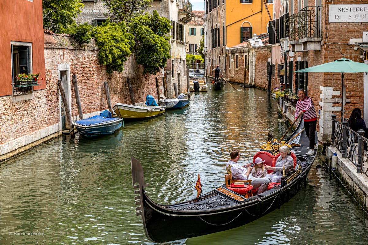 Tourists enjoying a gondola ride on a Venetian canal