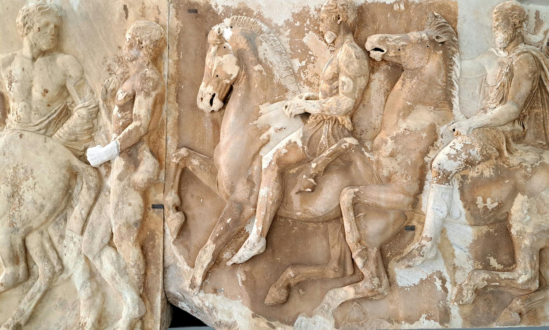 Detailed ancient Greek marble relief depicting riders on horseback