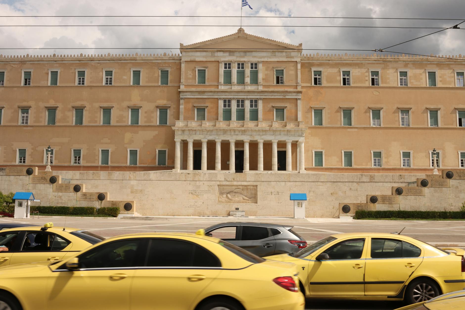 Hellenic Parliament building in Athens with yellow taxis in the foreground