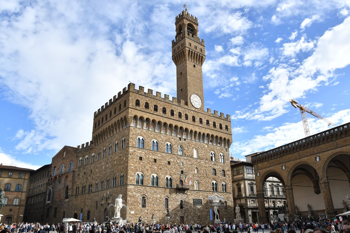 Palazzo Vecchio in Florence with visitors gathered in the piazza below