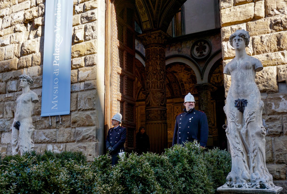 Guards standing by the statues at the entrance of Palazzo Vecchio museum in Florence Italy