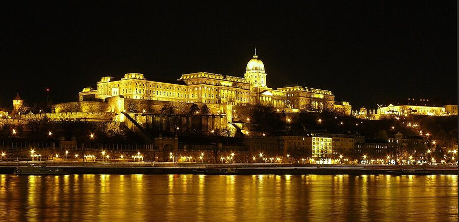 Buda Castle illuminated at night above the Danube