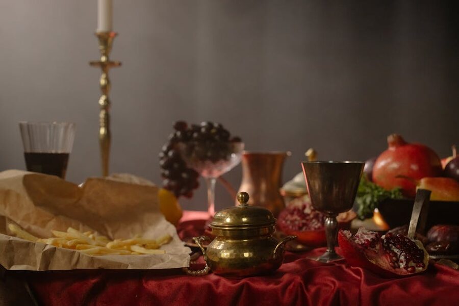 Metal goblets and platters arranged on a red tablecloth in renaissance still life