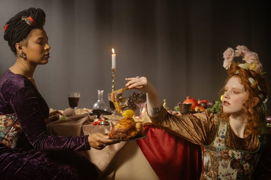 Two women in renaissance costumes sharing a vintage feast