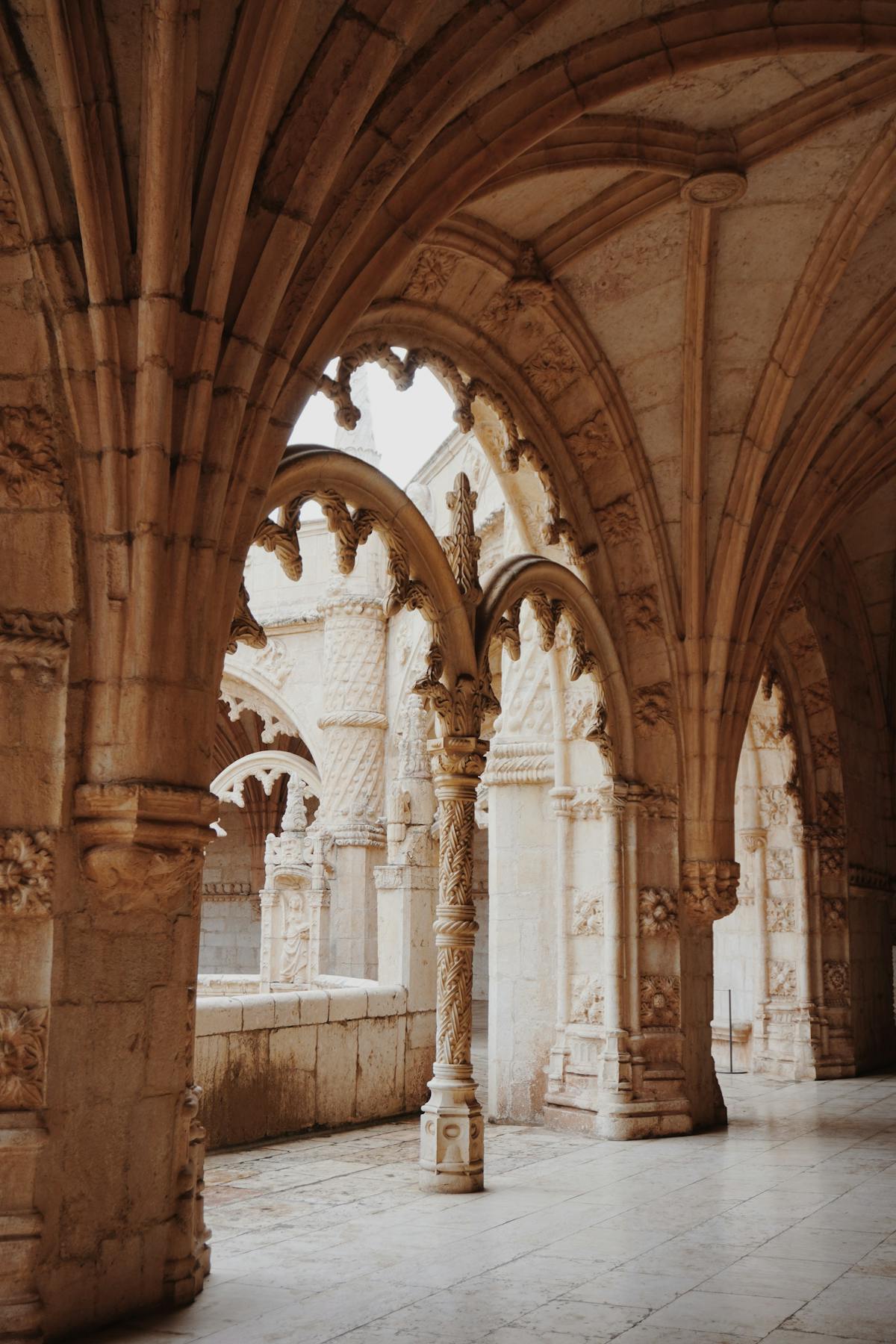 Stone arches and ornate columns inside the Jeronimos Monastery cloisters in Lisbon