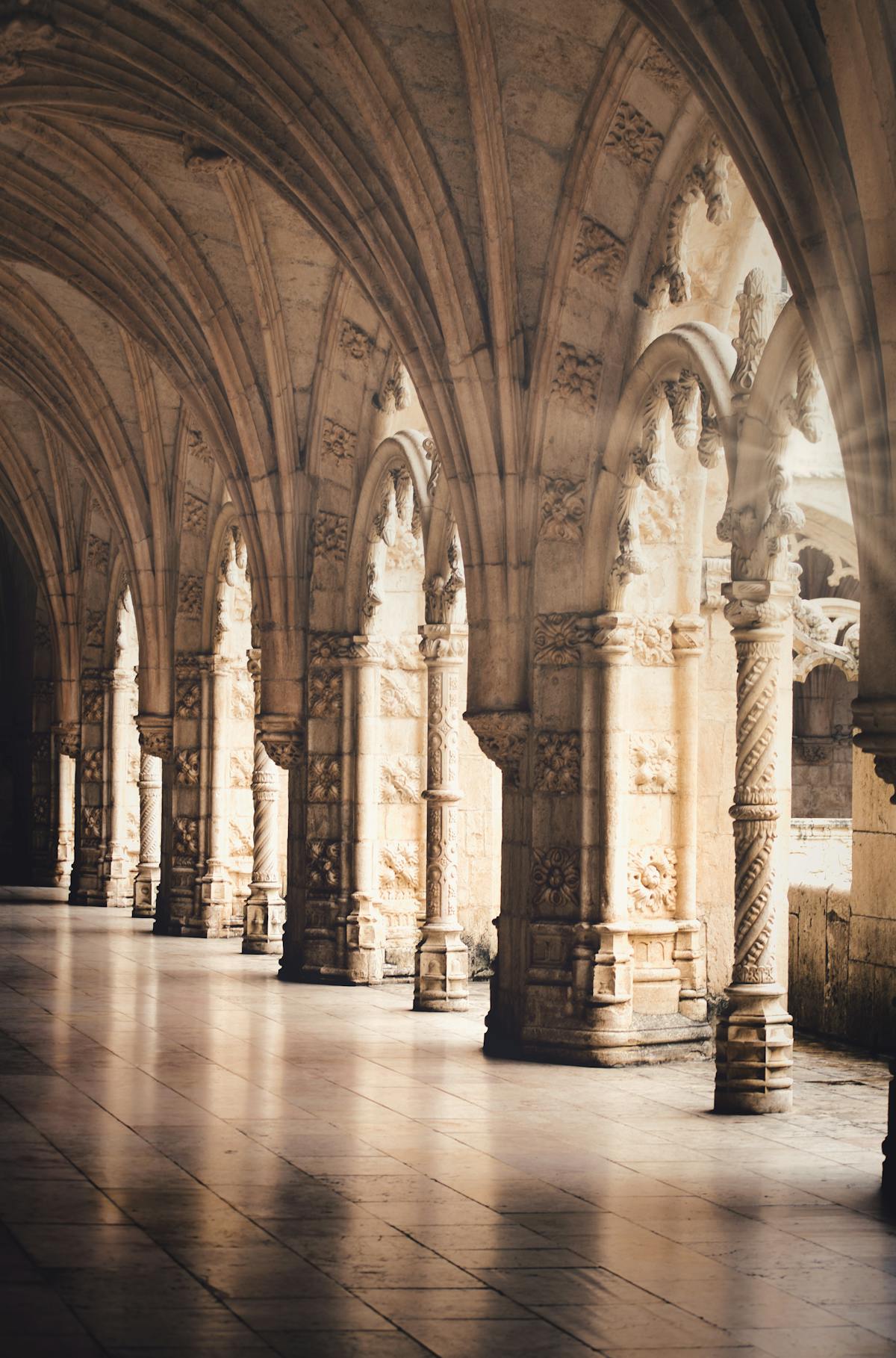 Stone columns inside Jeronimos Monastery bathed in warm afternoon light