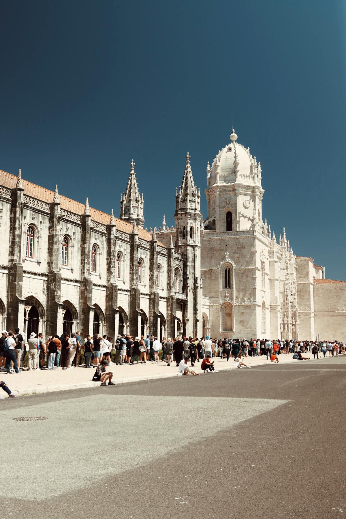 Gothic architectural details of Jeronimos Monastery with lush gardens in foreground