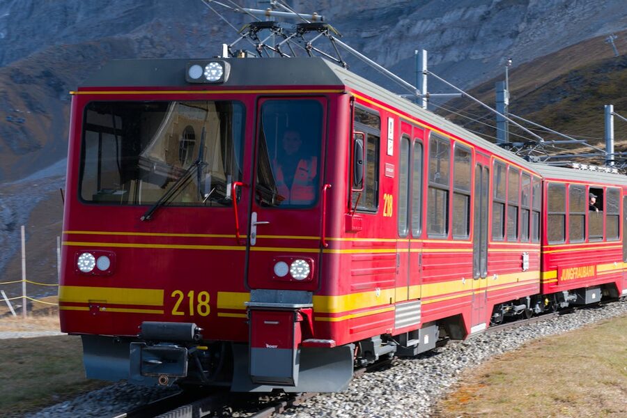 Red cogwheel train climbing through the Swiss Alps with mountain peaks in the background