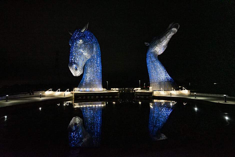 The Kelpies horse head sculptures lit up and reflected in water at night