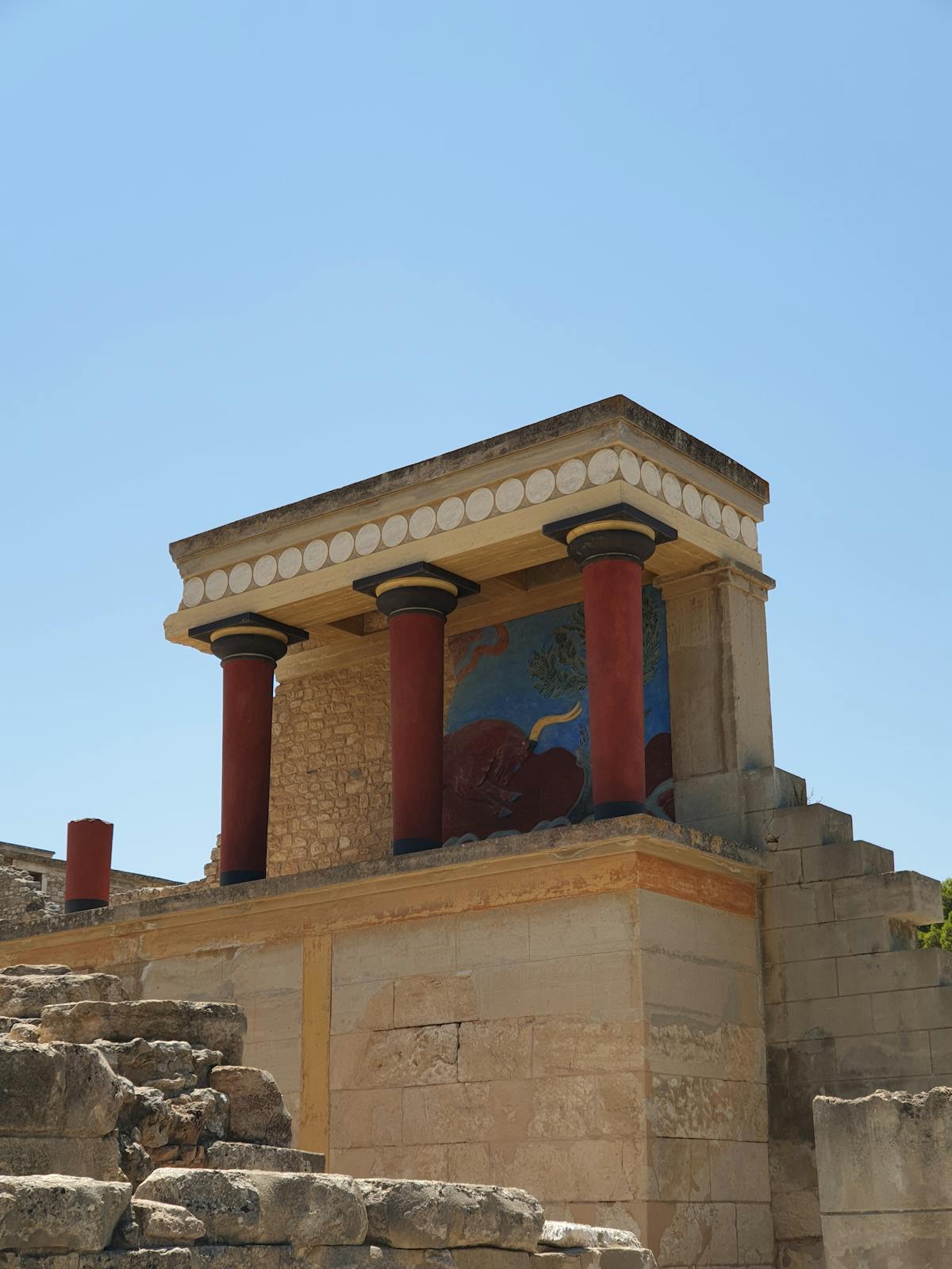 Red columns at Knossos Palace under clear blue sky