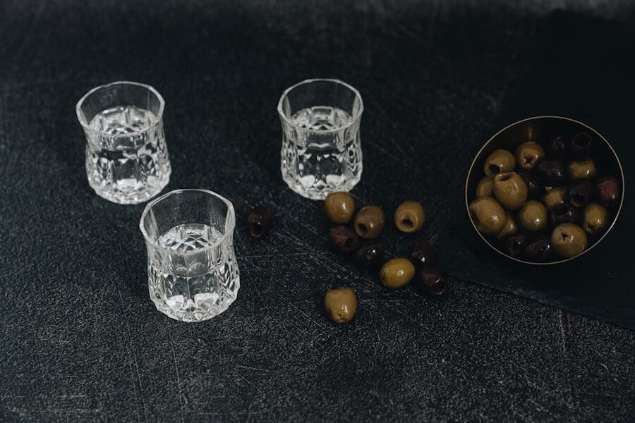 Crystal vodka shot glasses on a dark surface with olives