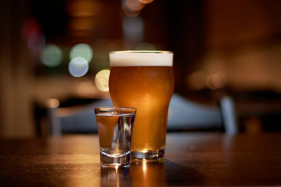 Beer glass and vodka shot on a pub table with bokeh lighting in Krakow