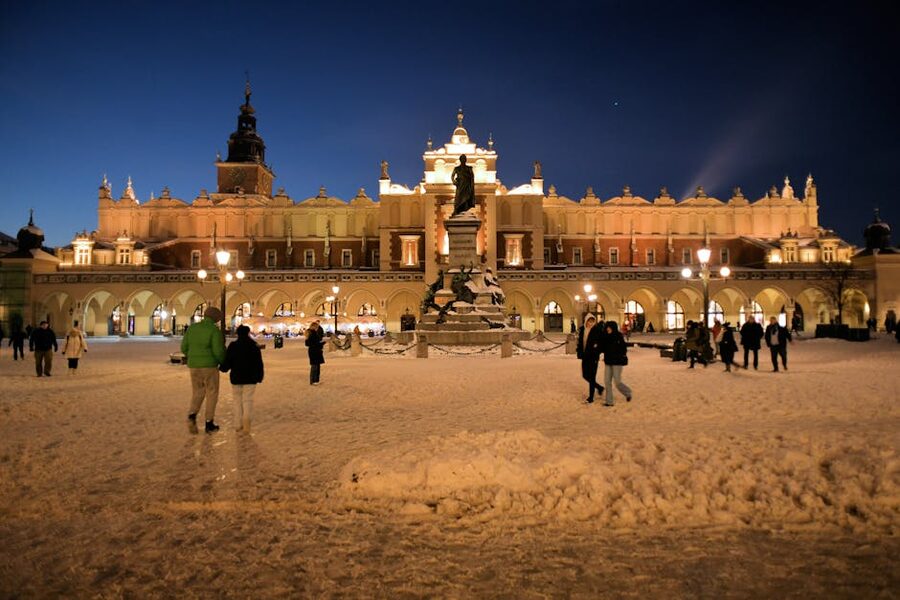 Sukiennice and Mickiewicz Monument in Krakow at night with snow