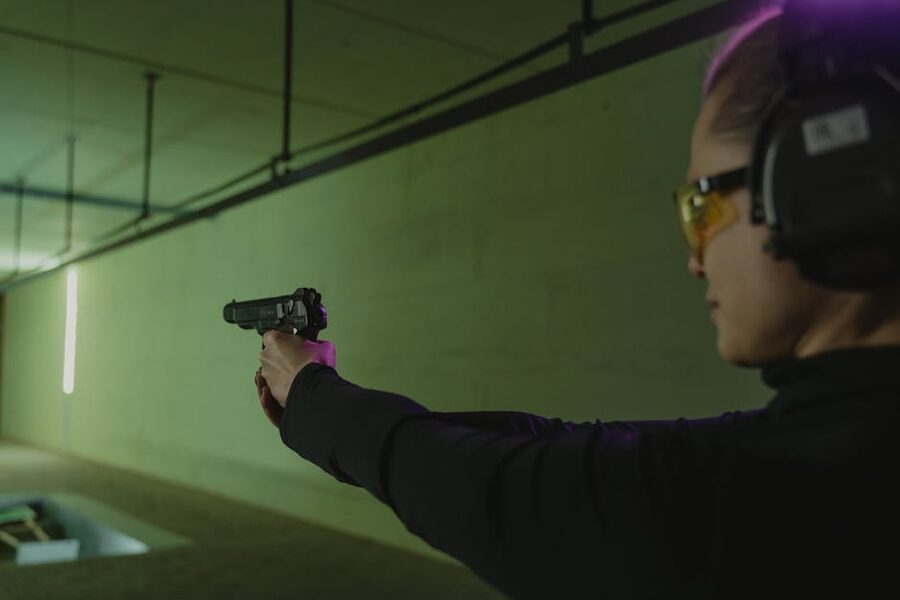 Focused shooter at indoor shooting range with safety gear and handgun