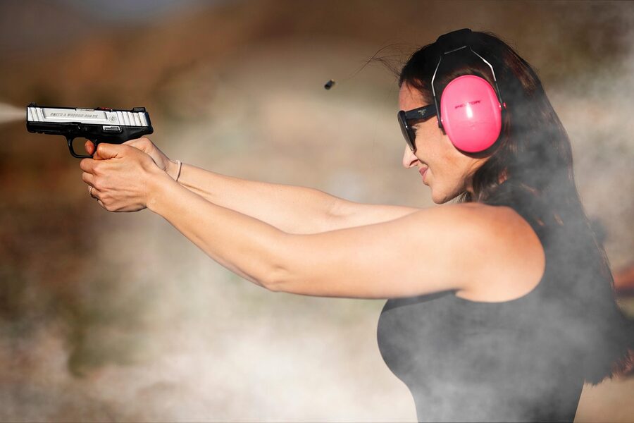 A handgun firing with muzzle smoke at an indoor shooting range