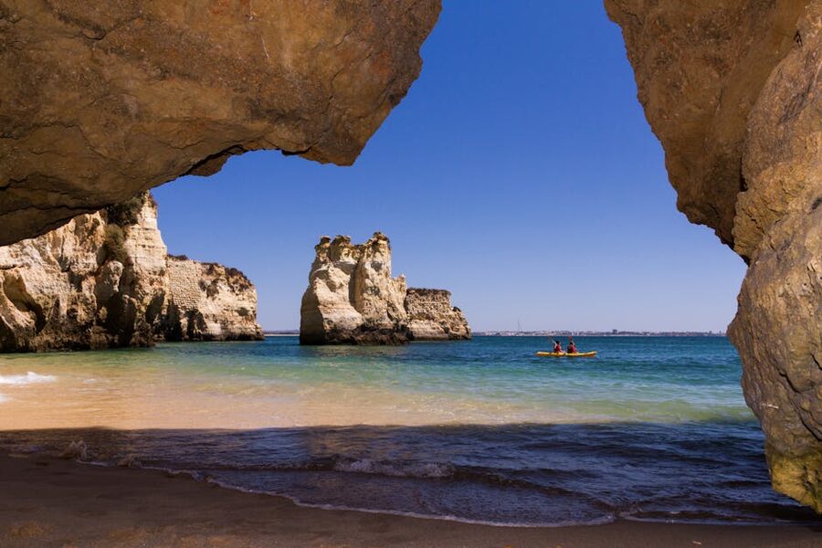 Kayakers paddling past limestone rock formations in Lagos, Algarve, Portugal