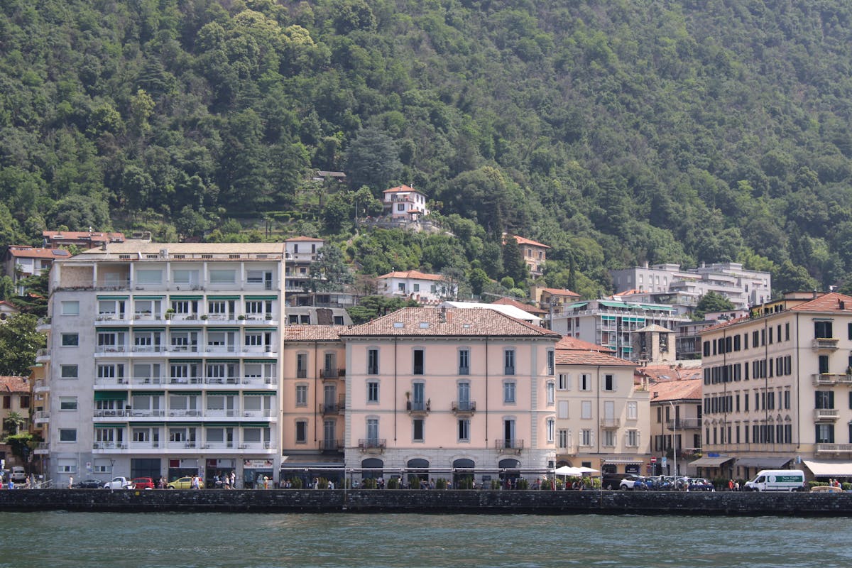 Lakeside architecture on Lake Como with green hills in the background
