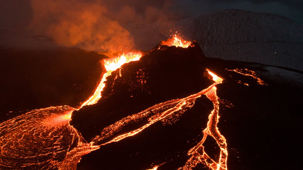 Aerial view of volcano erupting with flowing lava at night in Iceland