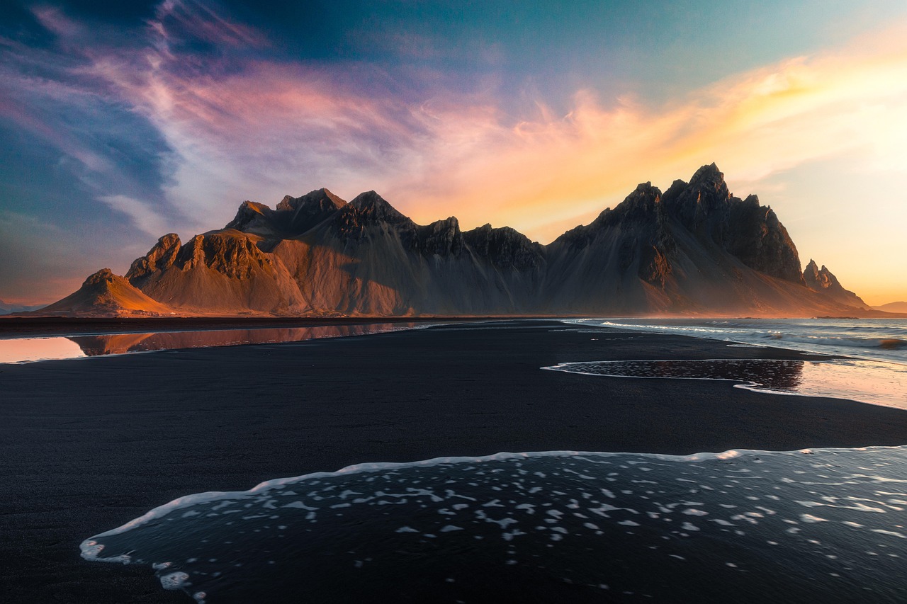 Vestrahorn mountain reflected on black sand beach at sunset in Iceland