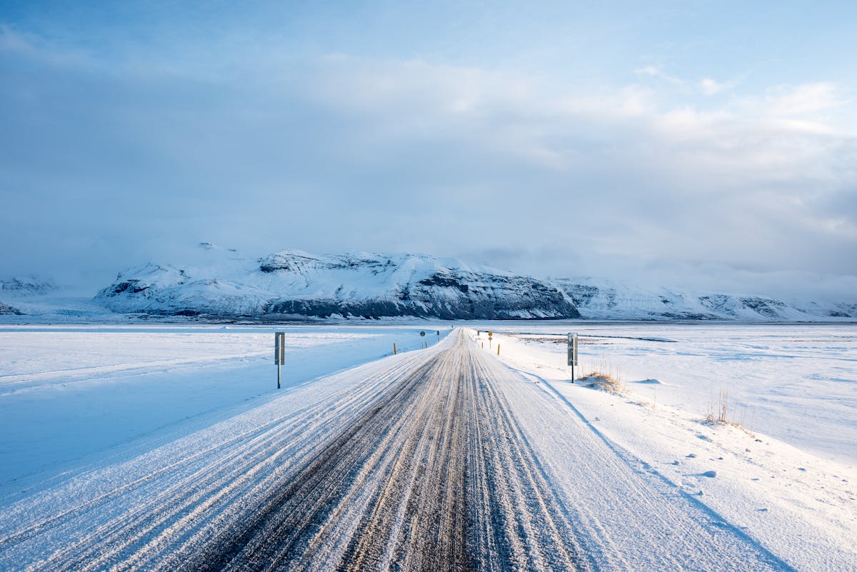 Snow-covered road leading toward mountains in Vik Iceland in winter