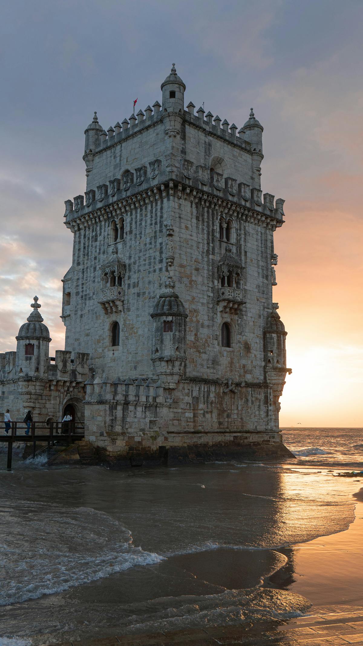 The Belem Tower standing against a colorful sunset on the Lisbon coastline