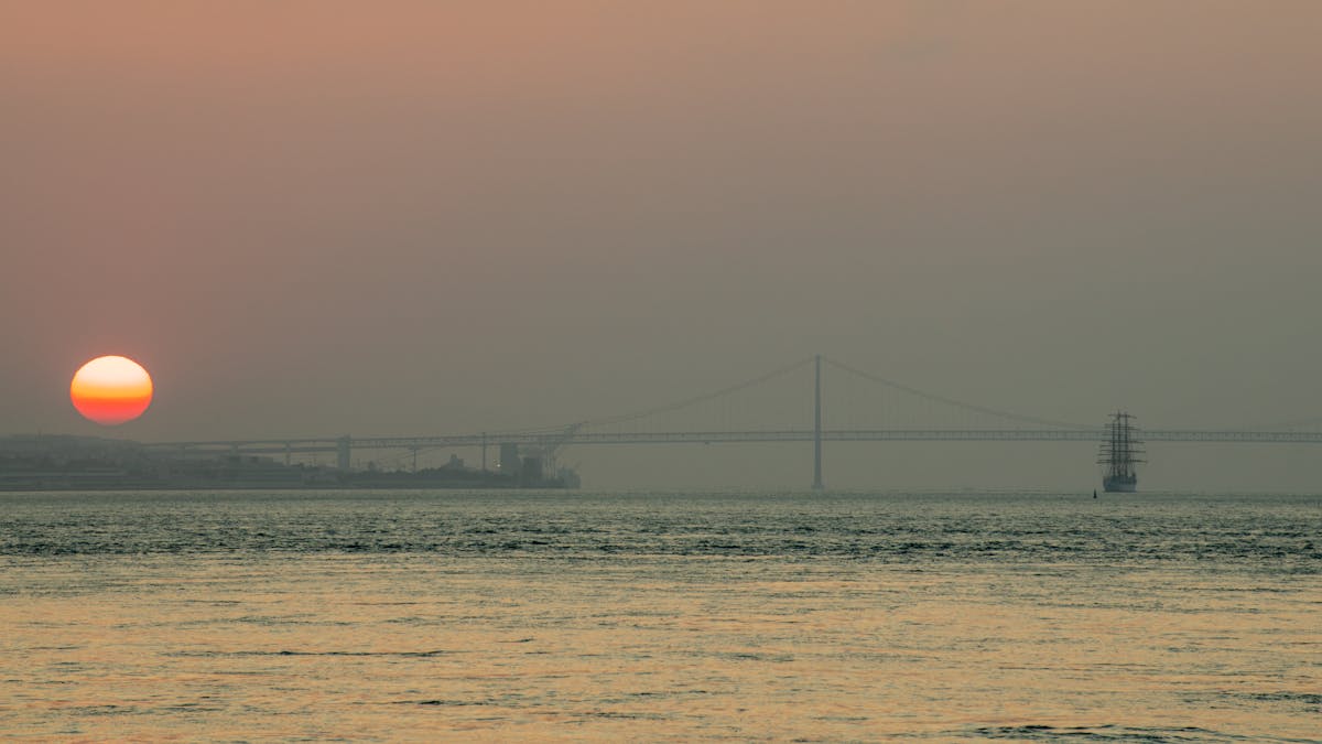 Sunrise view over the 25 de Abril Bridge and calm Tagus River in Lisbon