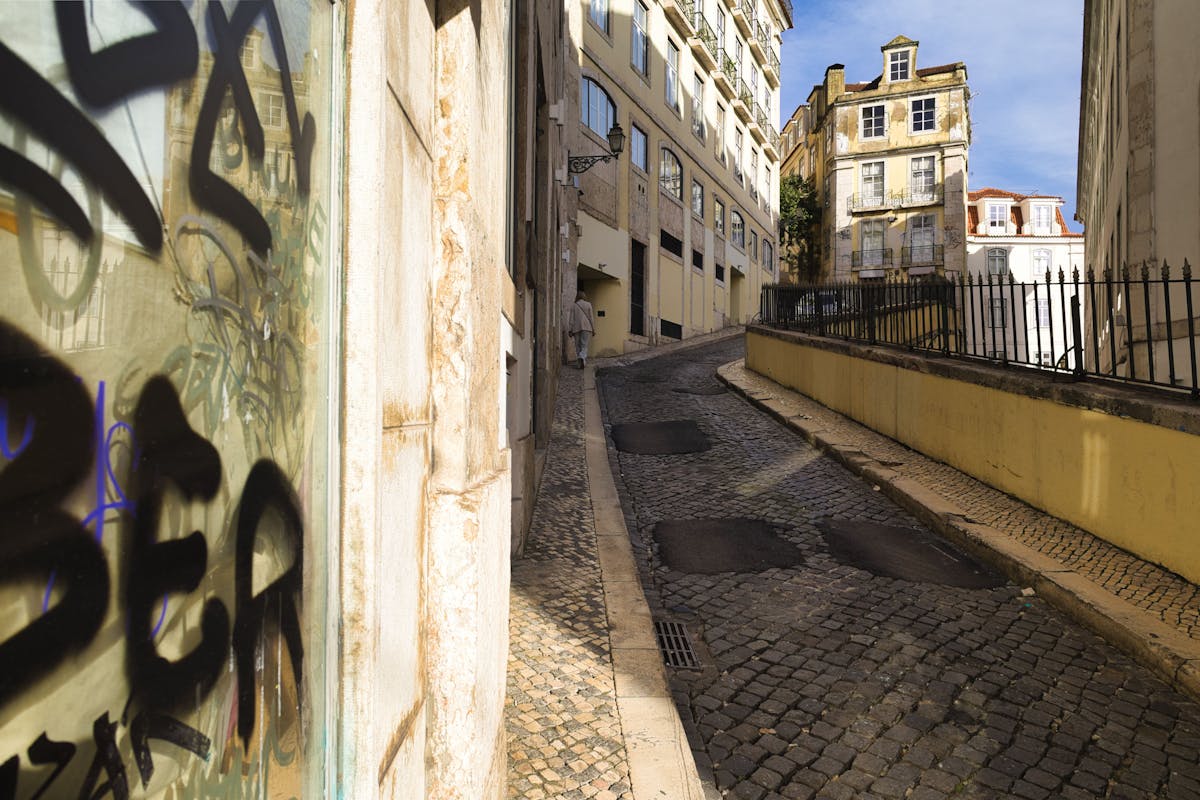 A scenic view of a narrow cobblestone street in Lisbon with colorful buildings