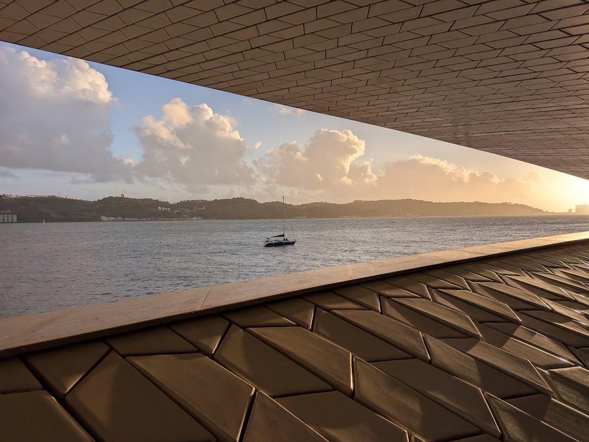 Modern Lisbon architecture with river view and sailboat at sunset