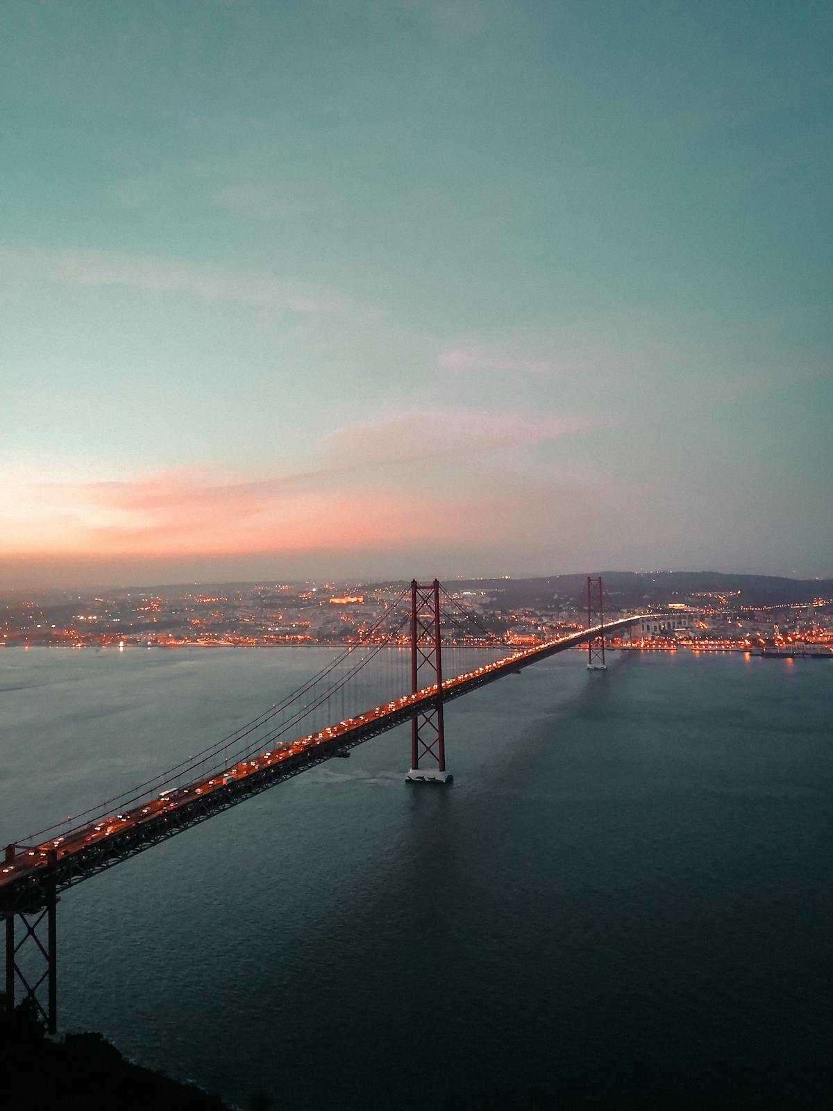 Golden sunset over Ponte 25 de Abril bridge and Lisbon cityscape