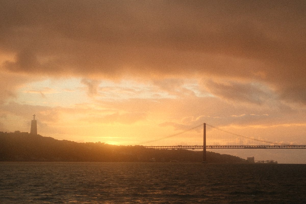 Sunset view of the 25 de Abril Bridge and Cristo Rei statue over the Tagus River in Lisbon