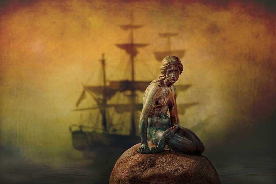The Little Mermaid bronze statue sitting on a rock by the water in Copenhagen Denmark