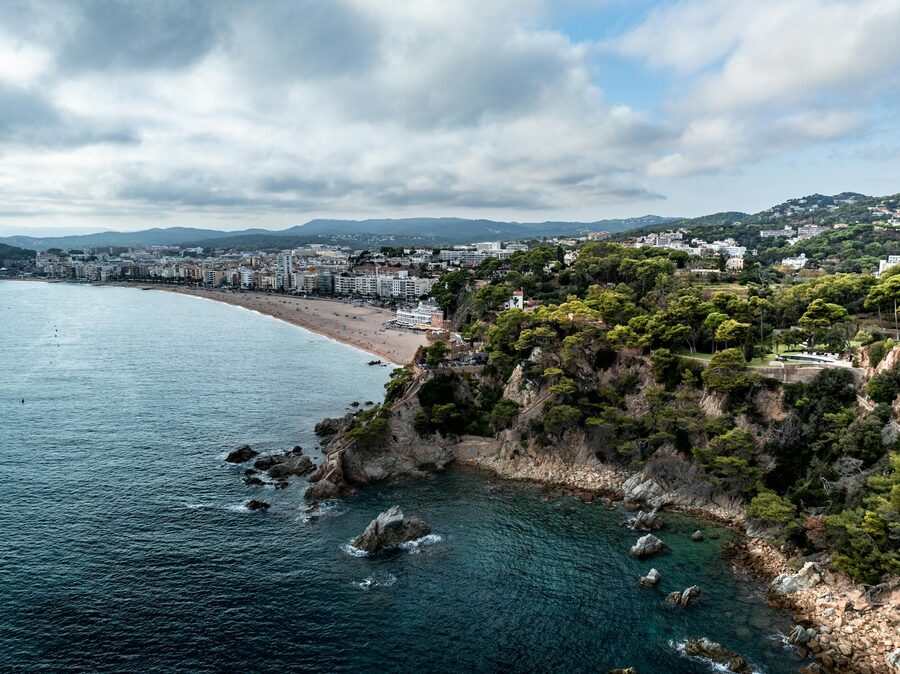 Sandy beach and green cliffs along the Lloret de Mar coastline