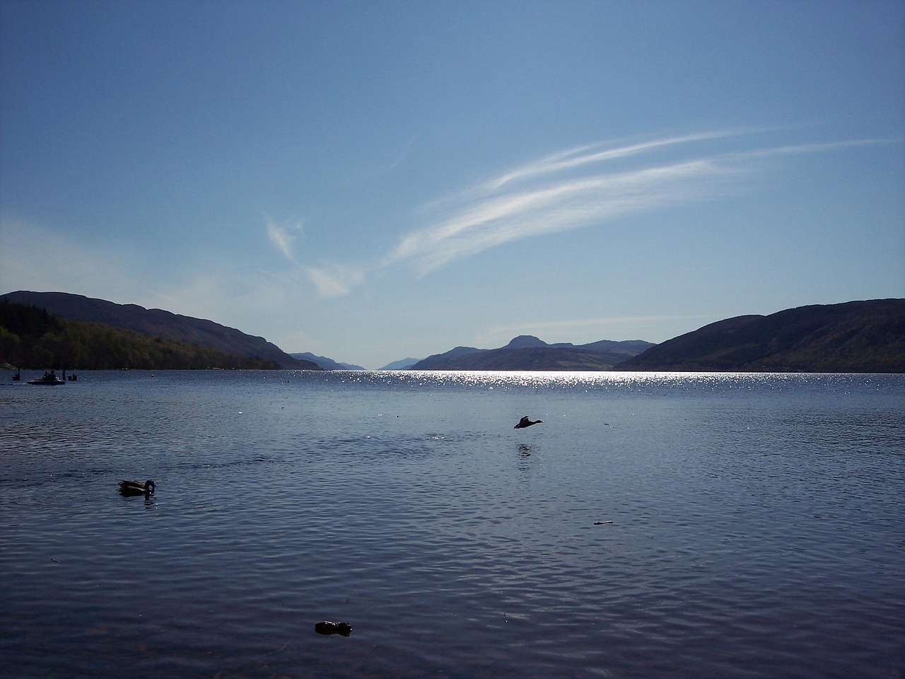 Calm waters of Loch Ness reflecting surrounding hills and sky