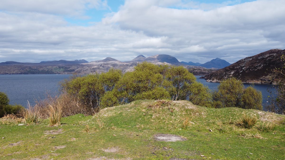 Loch and mountains in Scottish Highlands under cloudy skies