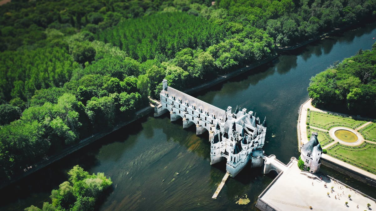 Aerial photograph showing Chenonceau castle spanning the river surrounded by green forest