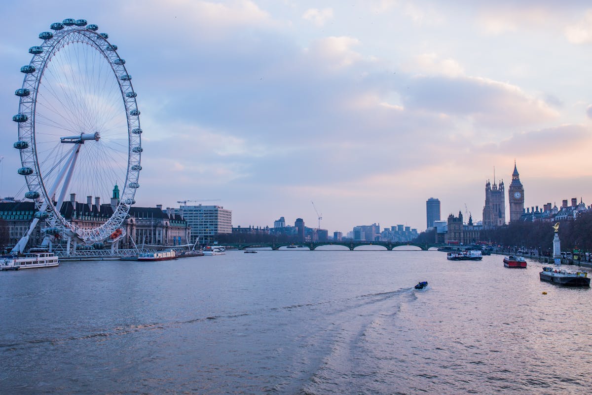 Golden hour light falling across the London Eye and Big Ben from across the Thames