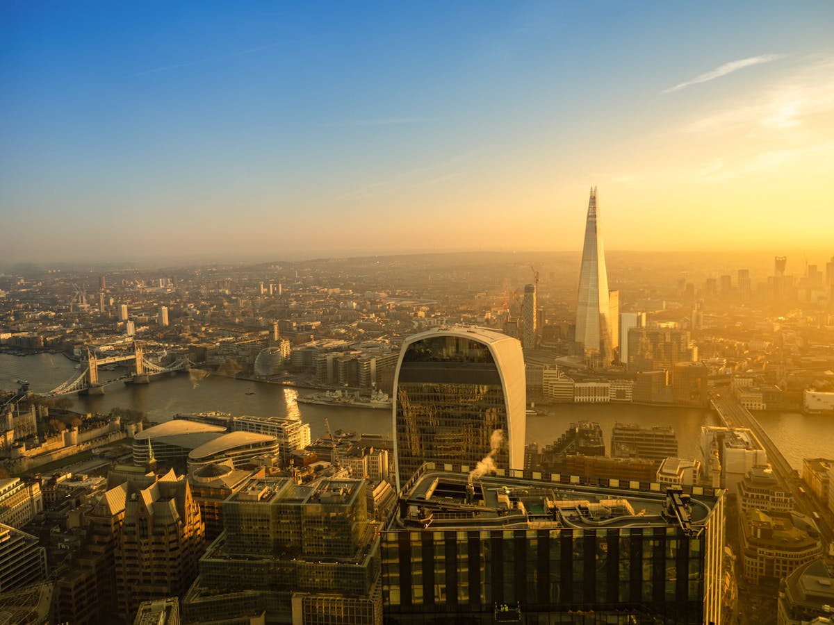 An aerial view of London's skyline at sunset with the Shard and Tower Bridge visible