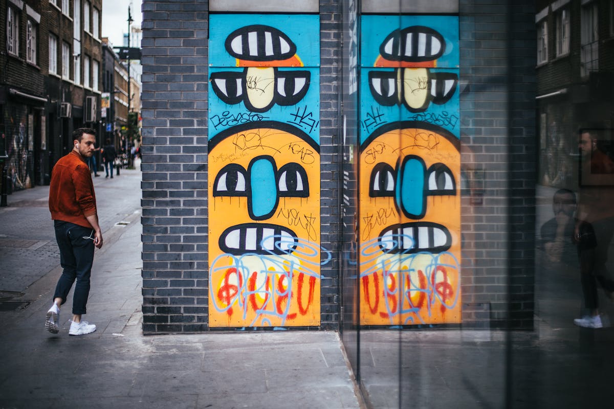 Person walking past colorful graffiti art on a London wall