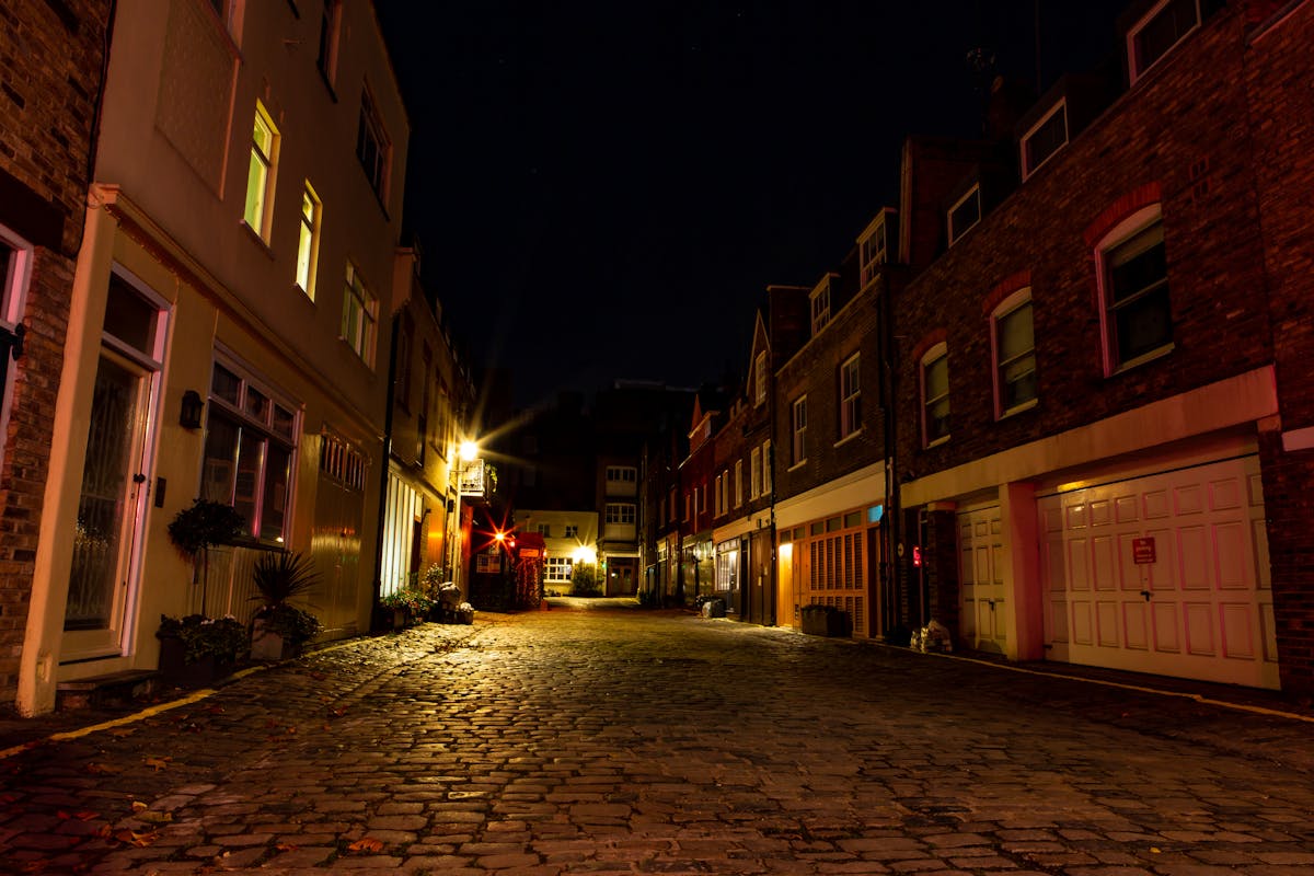 Atmospheric cobblestone alley lit by warm lights at night in London