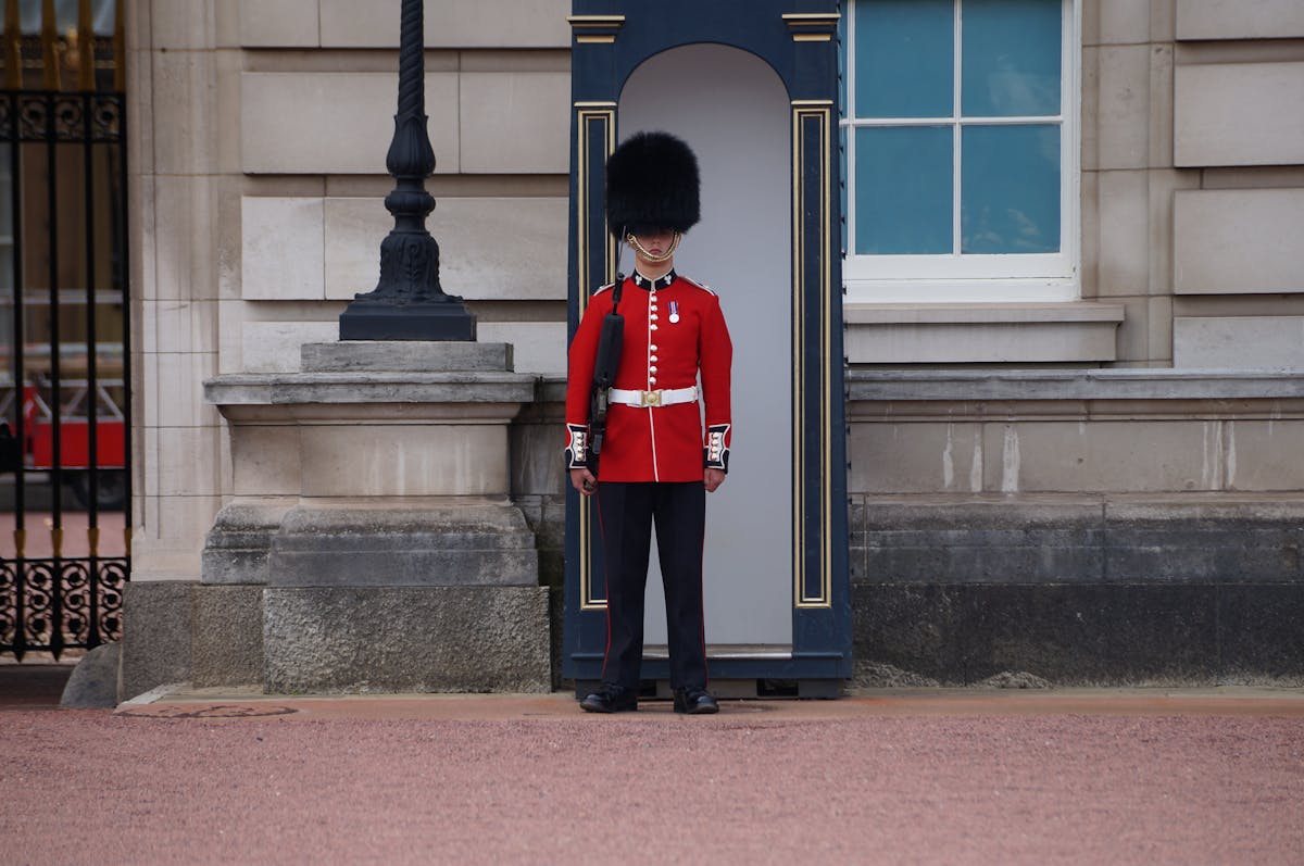 Royal guard in red uniform standing outside Buckingham Palace London