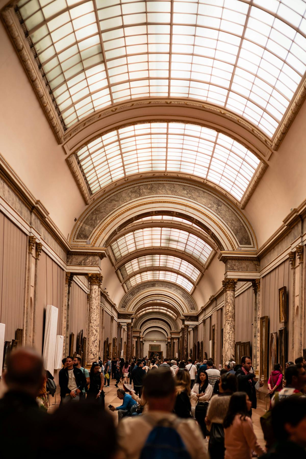 Busy hallway inside the Louvre Museum with visitors walking through galleries